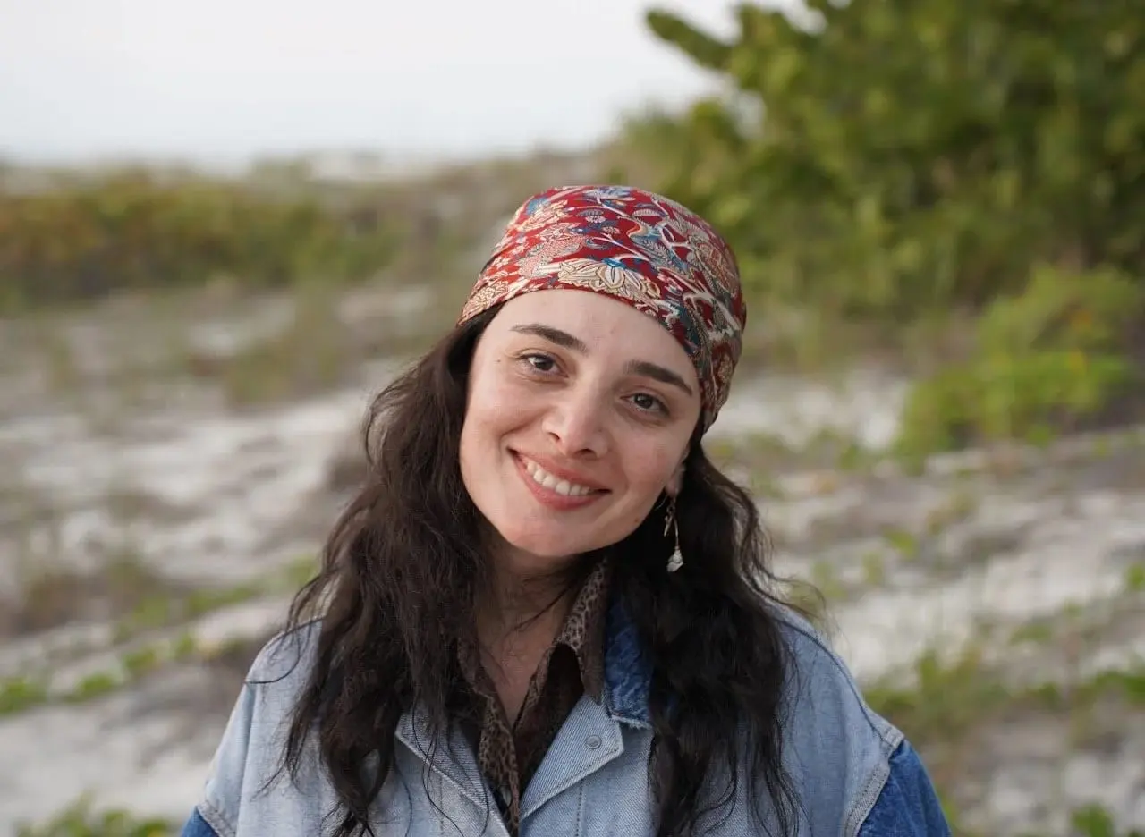 Lia Komakhidze, director and co-producer, smiling outdoors in a colorful headscarf and denim jacket.